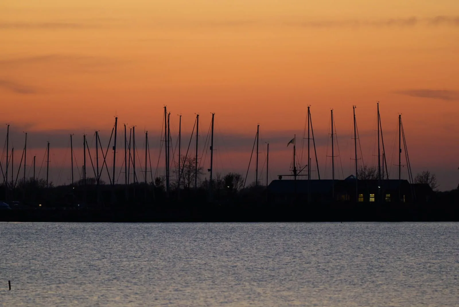 Masten im Lemkenhafener Hafen unter orangefarbenem Abendhimmel